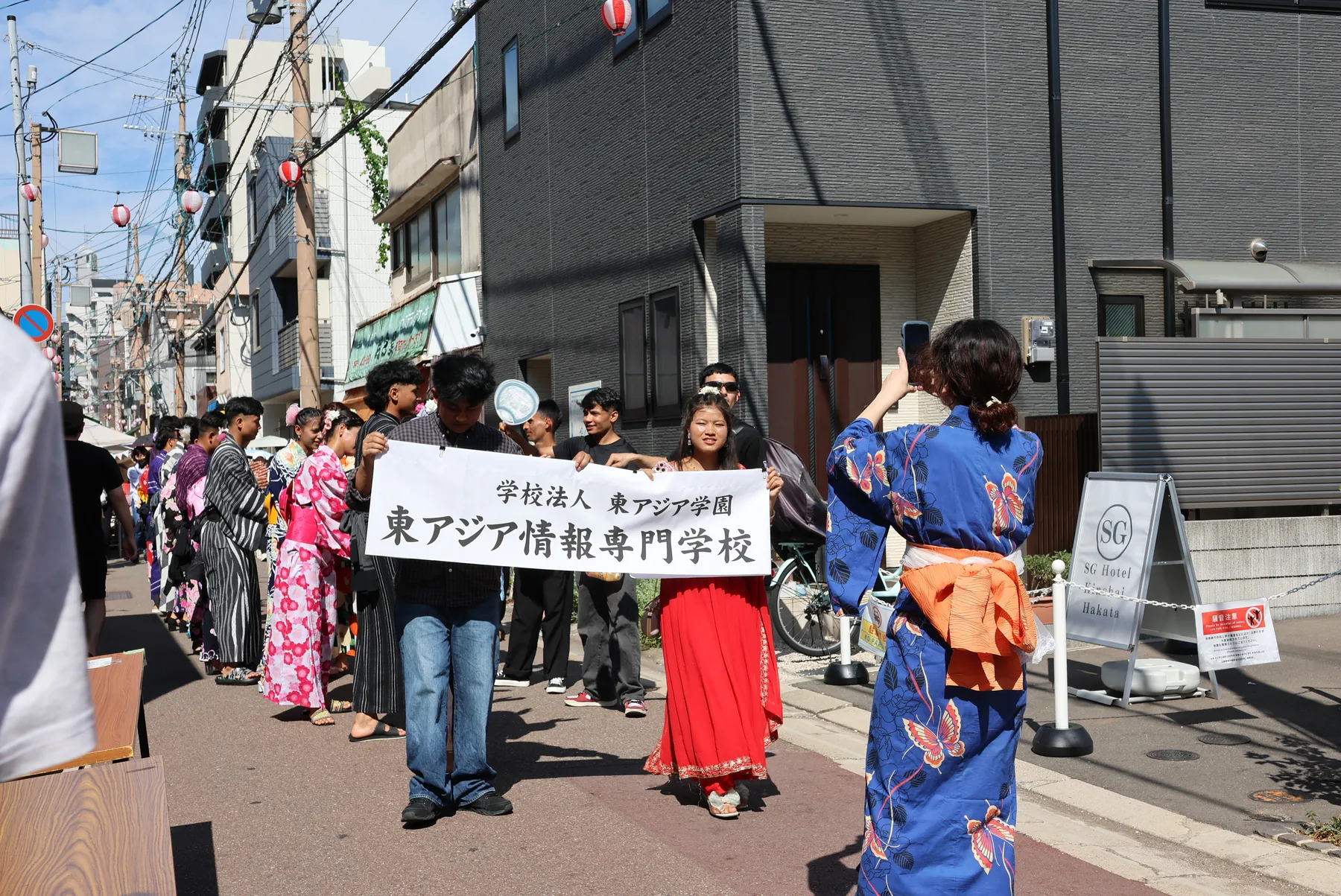東アジア情報専門学校の横断幕を持って商店街を進む学生たち